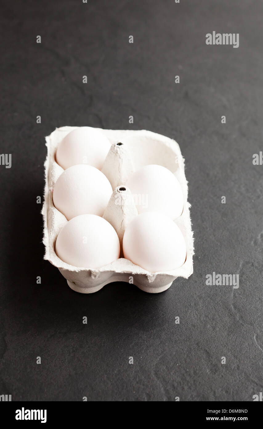 Chicken eggs in white carton on dark background Stock Photo