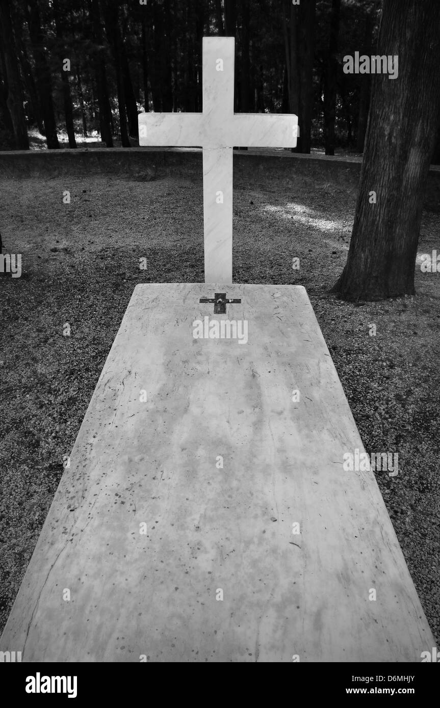 Cross and marble grave tombstone among trees. Stock Photo