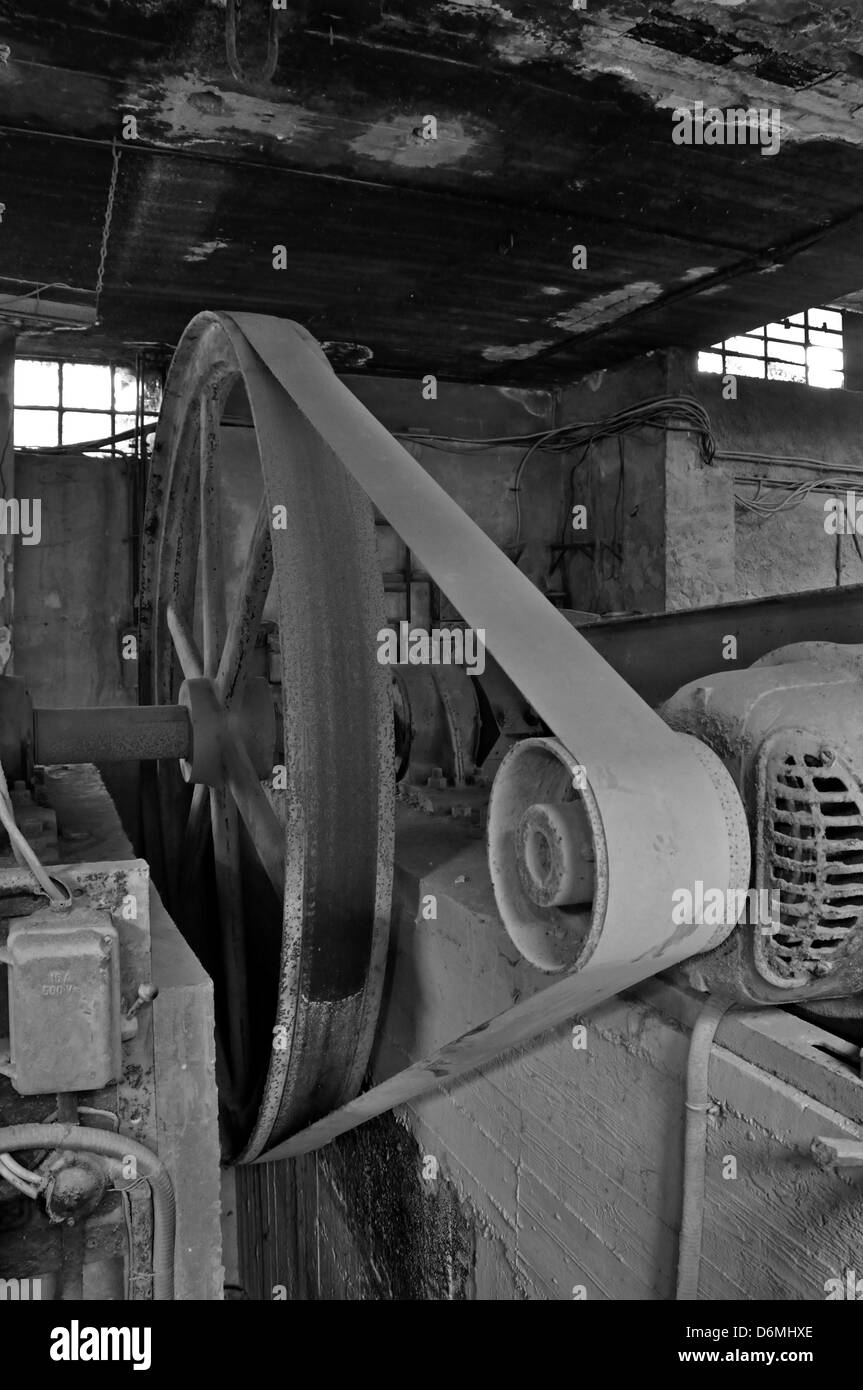 Rusty wheel belt driven machinery in abandoned factory interior. Black and white. Stock Photo