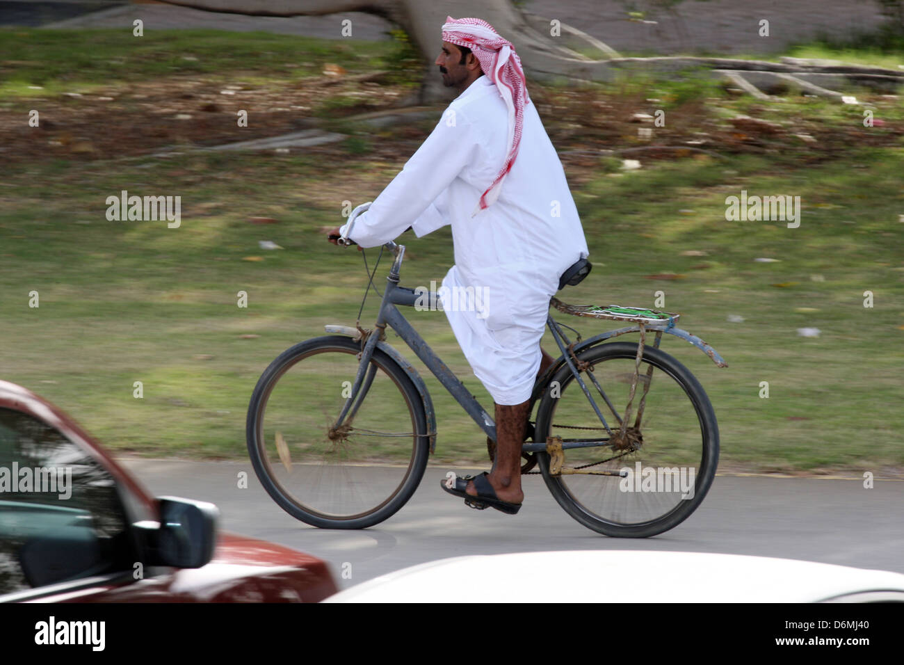 Dubai man in national costume rides a bicycle Stock Photo