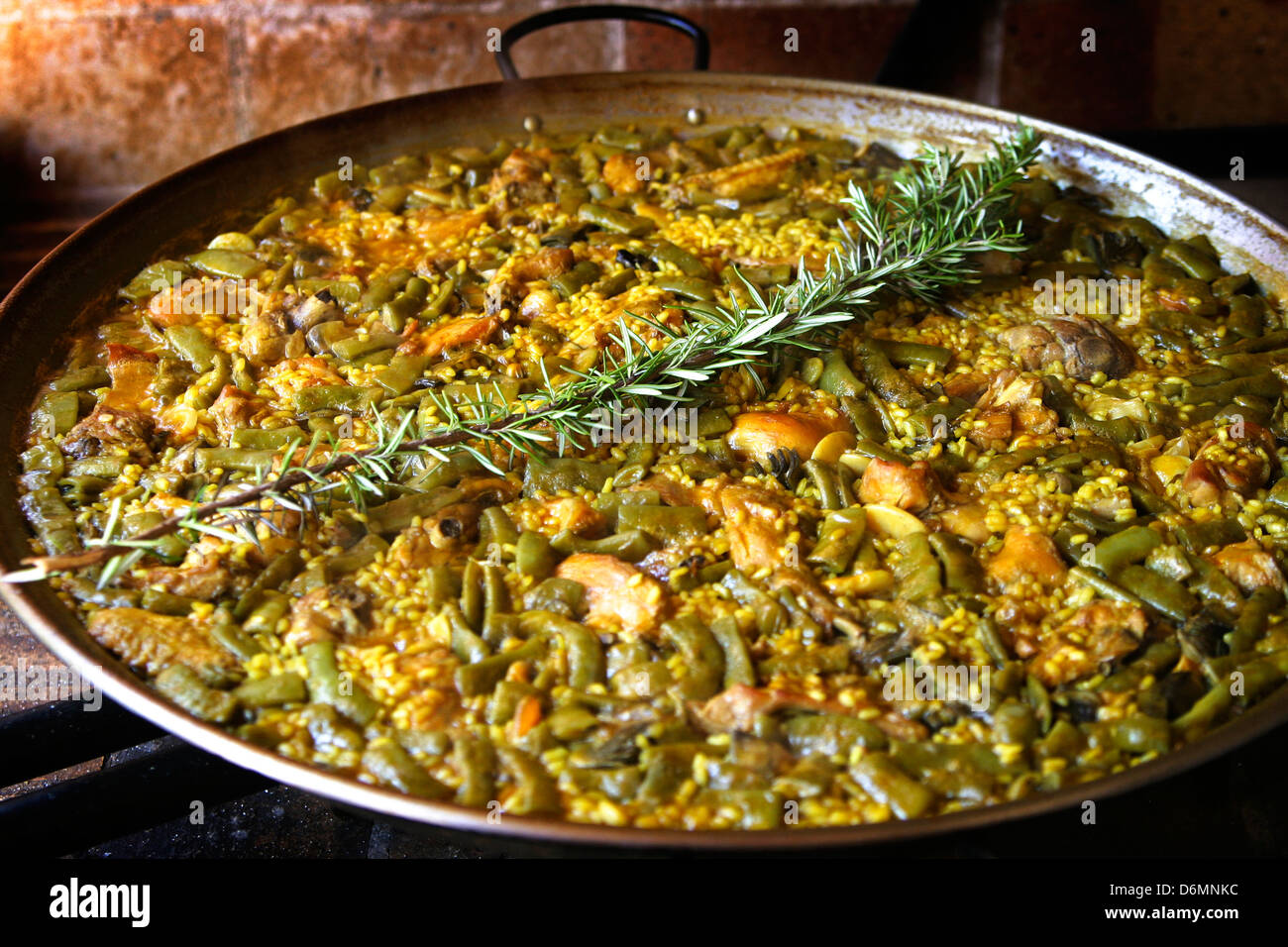 Paella Pan with chicken and rabbit paella, cooked on wood Stock Photo