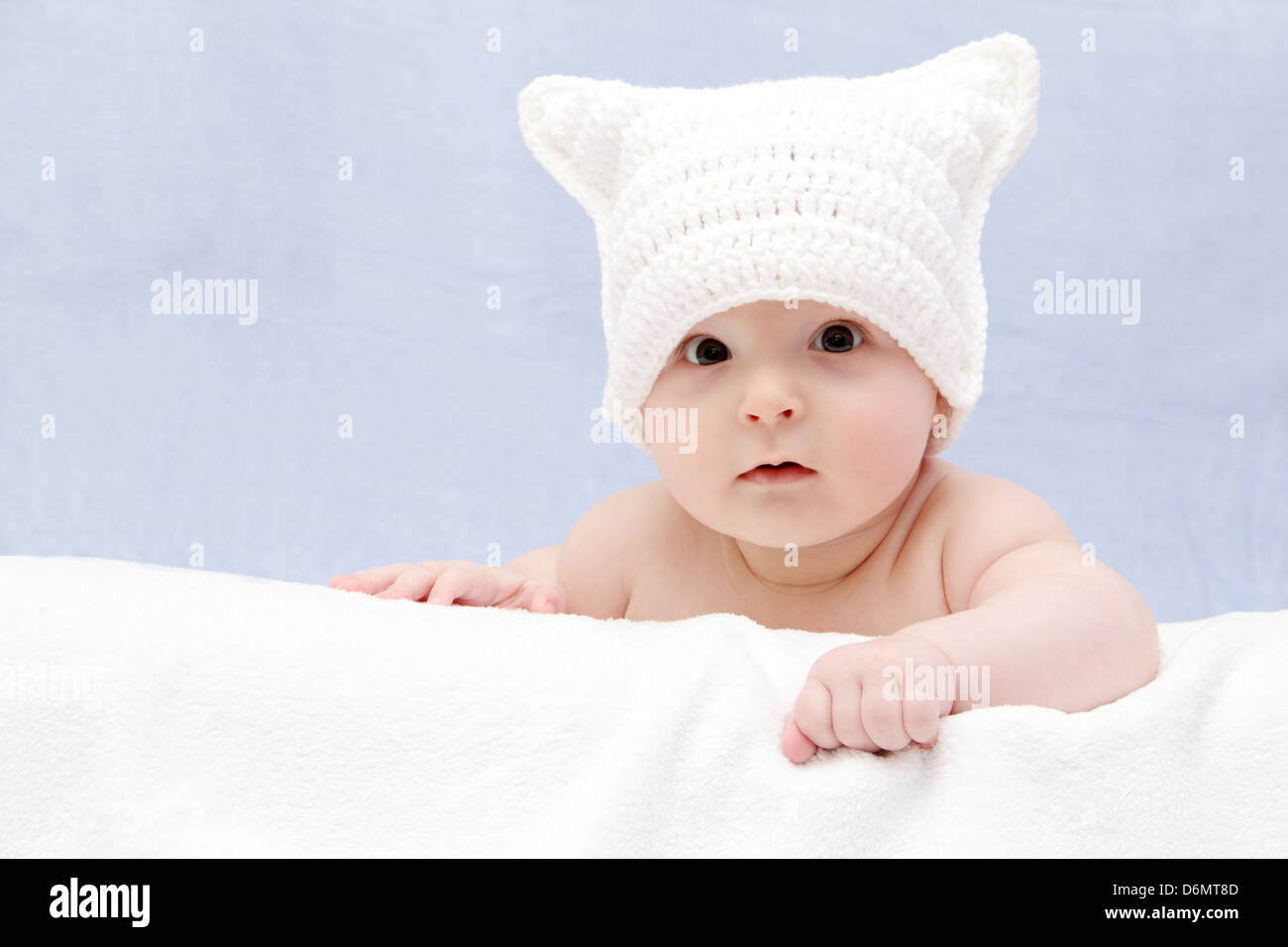 Beautiful baby in white hat lies on bed Stock Photo