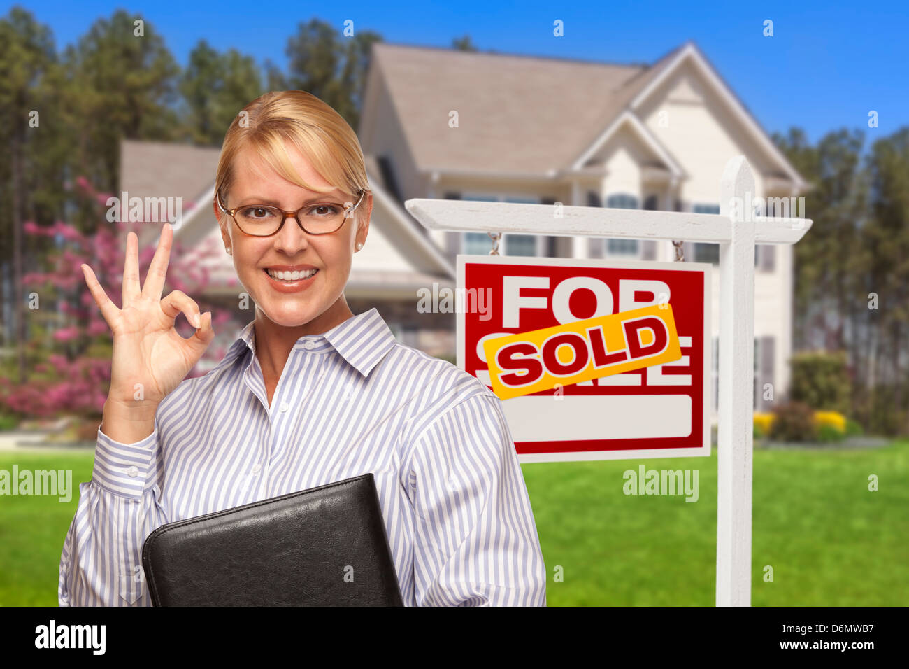 Female Real Estate Agent in Front of Sold Home For Sale Sign and House