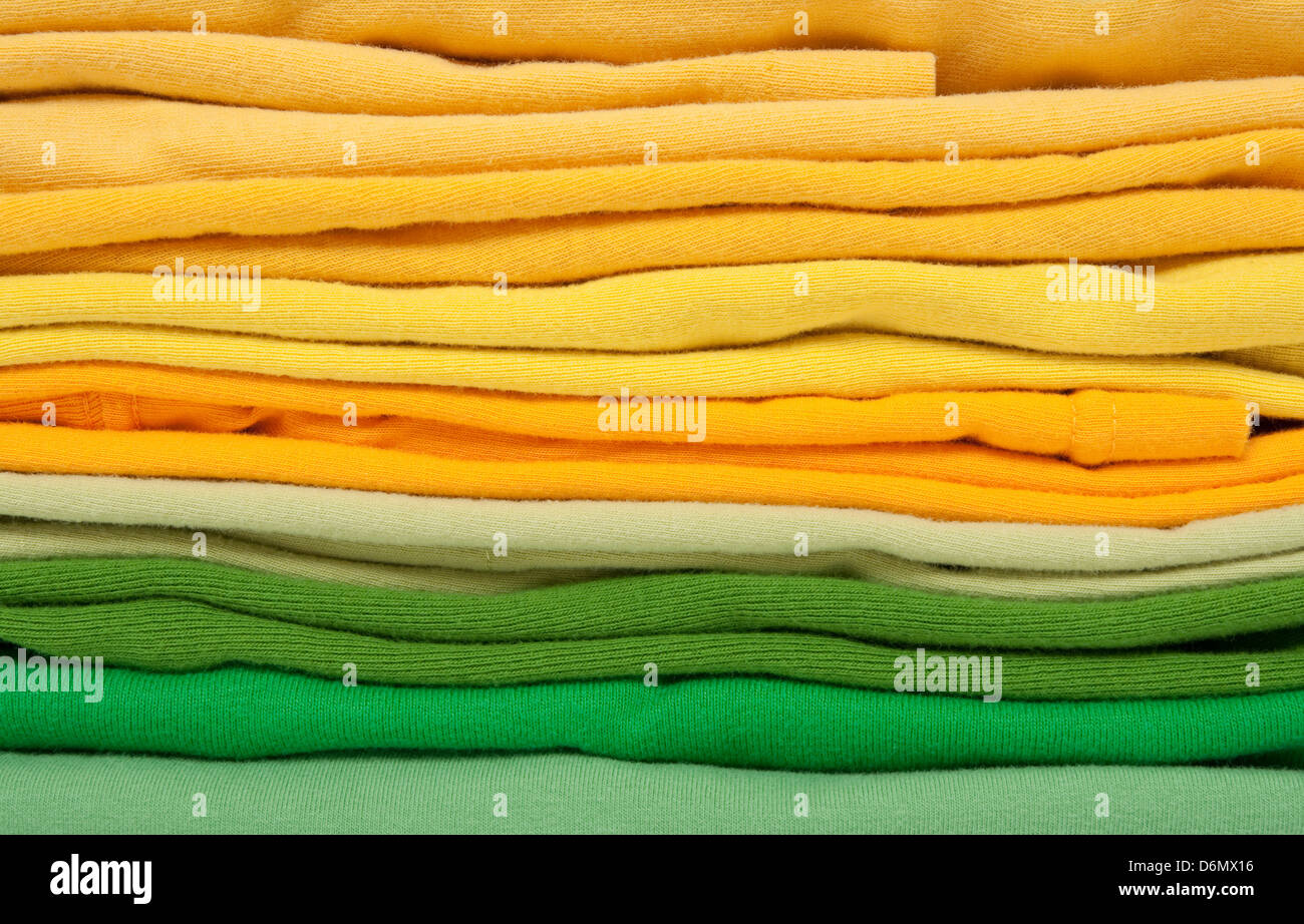 Background of folded joyful green and yellow clothes. Stock Photo