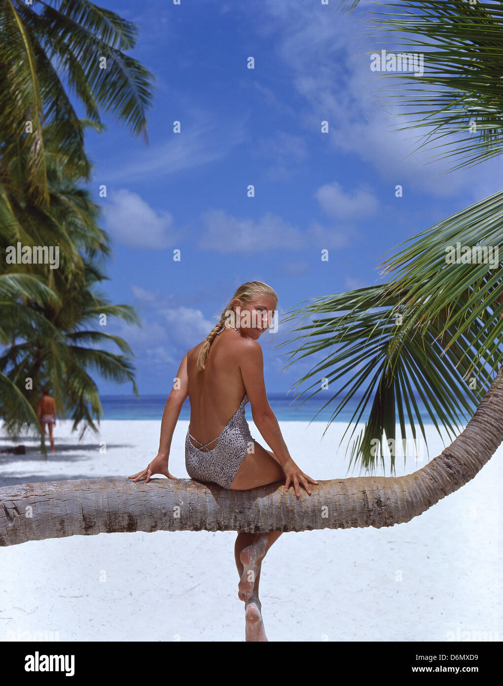 Young woman sitting on palm tree, Kuda Bandos, Bandos Island, Kaafu Atoll, Republic of Maldives Stock Photo