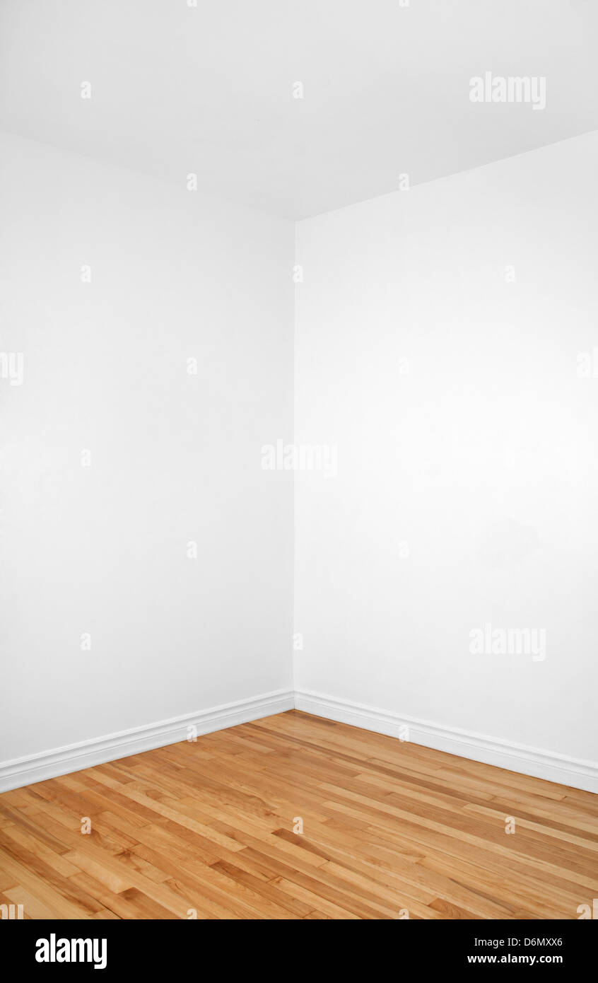 Empty corner of a renovated room with white walls and wooden floor