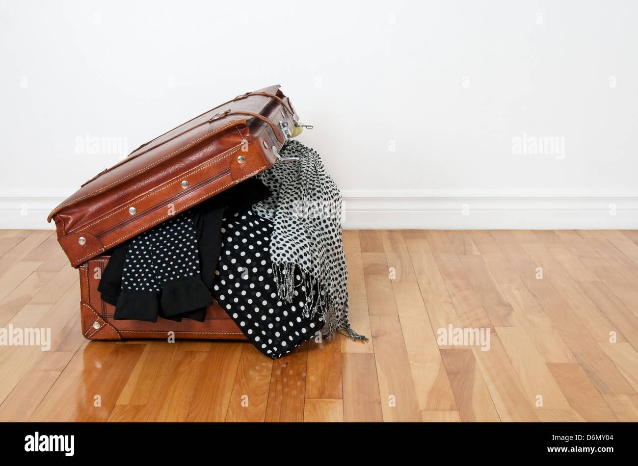 Black and white polka dot clothes in a retro leather suitcase. Stock Photo
