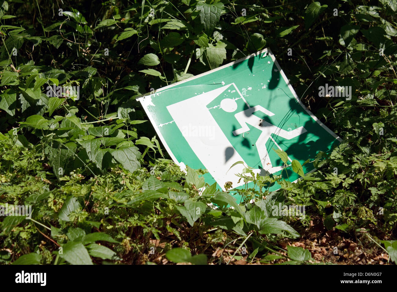 Beelitz, Germany, had fallen down emergency exit sign in the bushes Stock Photo