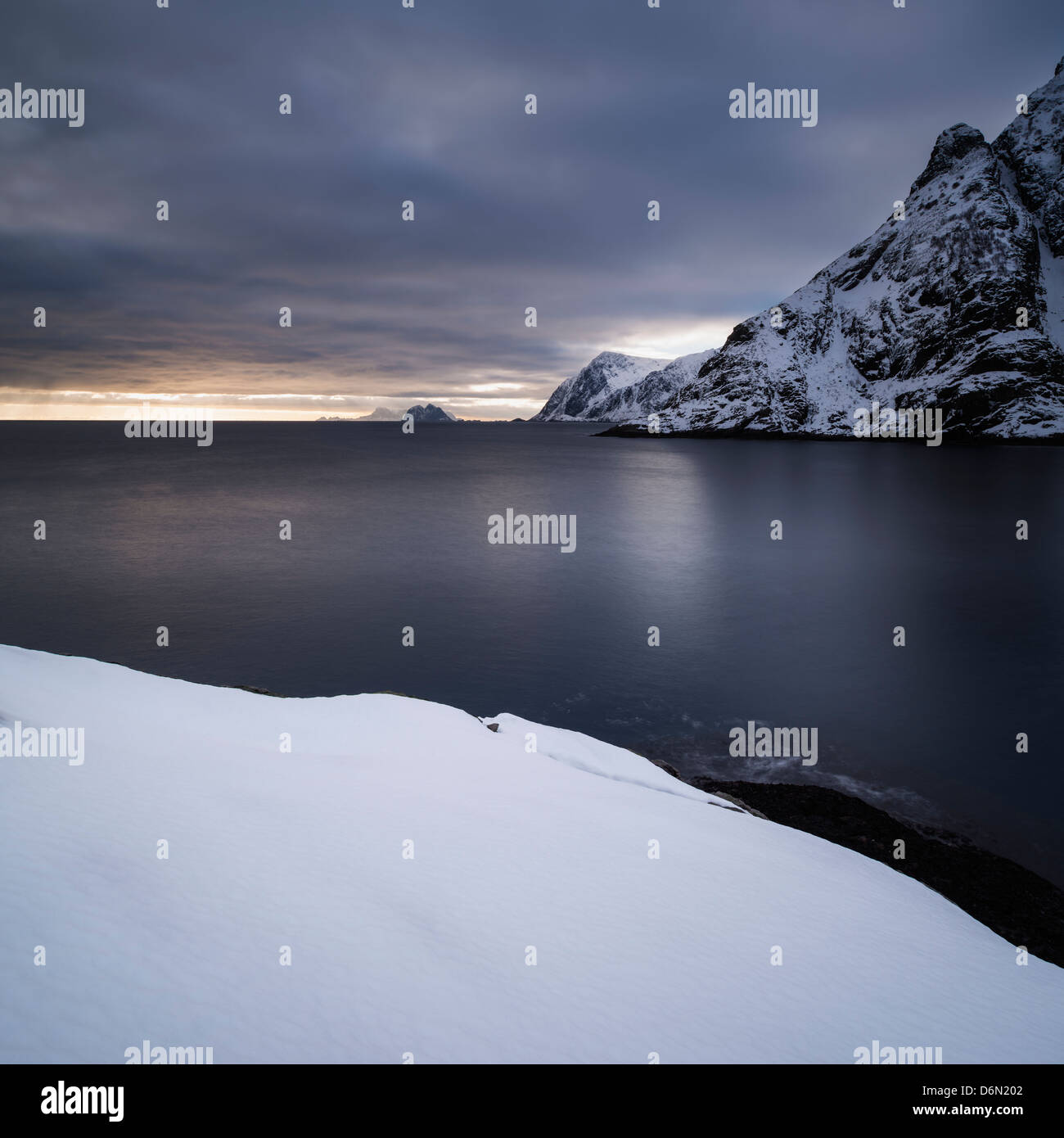 Snow covered mountains rise from sea, Å, Moskenesøy, Lofoten Islands, Norway Stock Photo