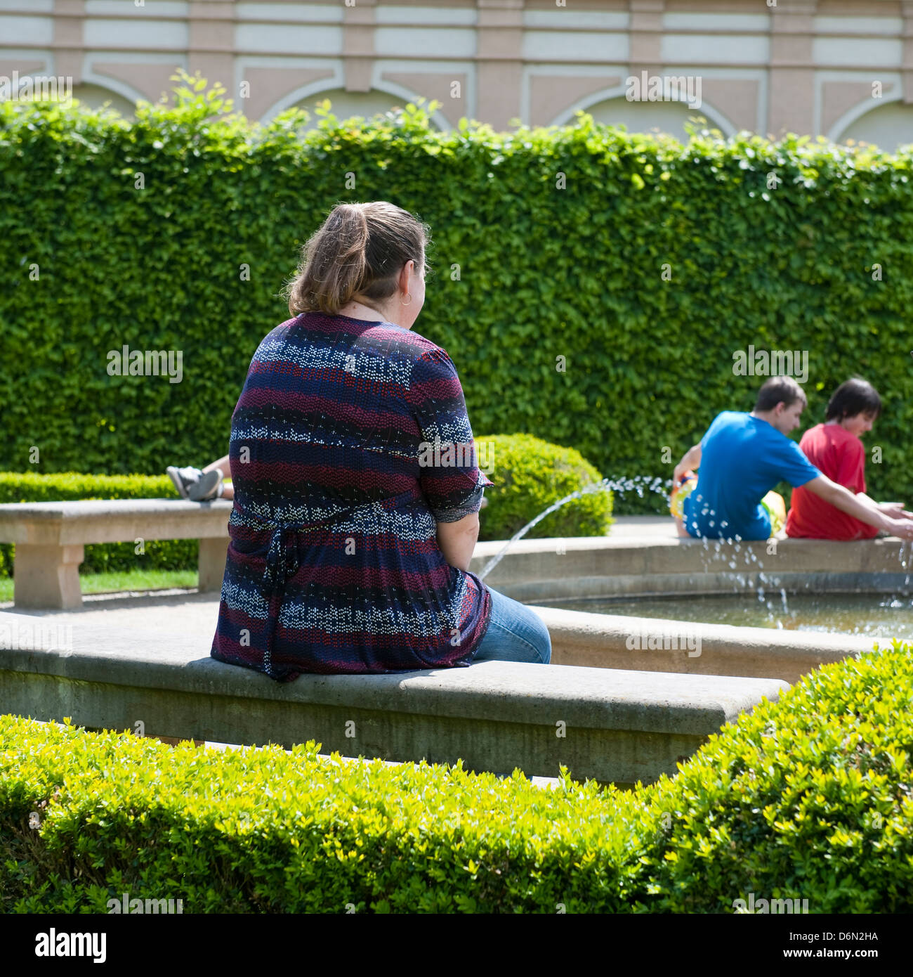 Woman sitting by a fountain, Prague Stock Photo