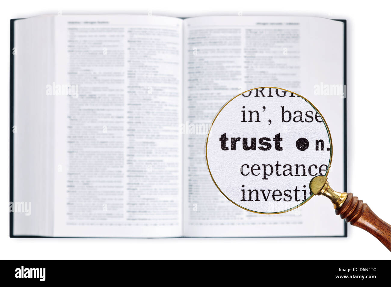 A magnifying glass held over a dictionary looking at the word TRUST enlarged Stock Photo