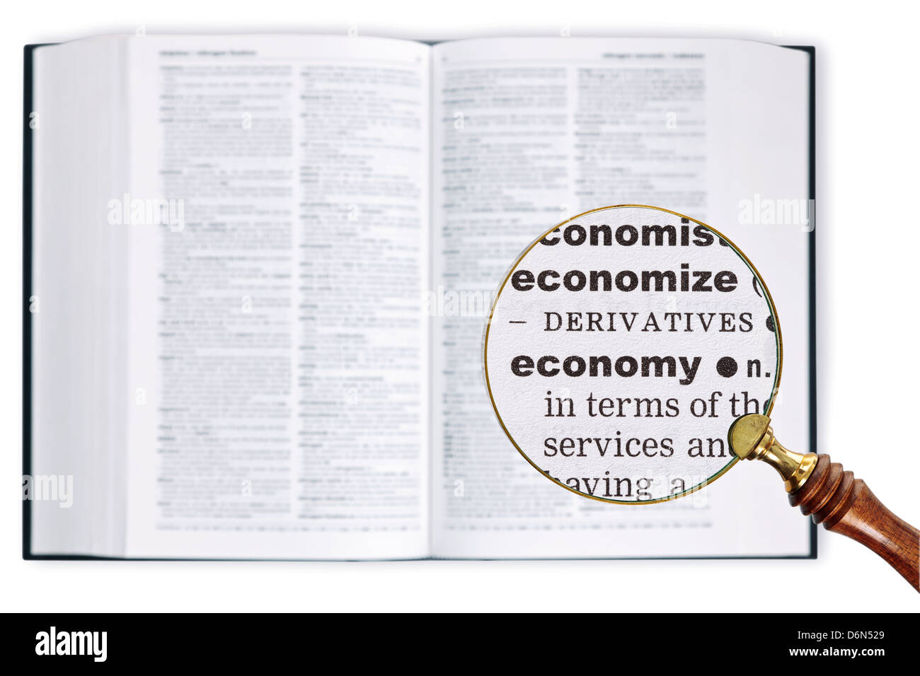 A magnifying glass held over a dictionary looking at the word ECONOMY enlarged Stock Photo