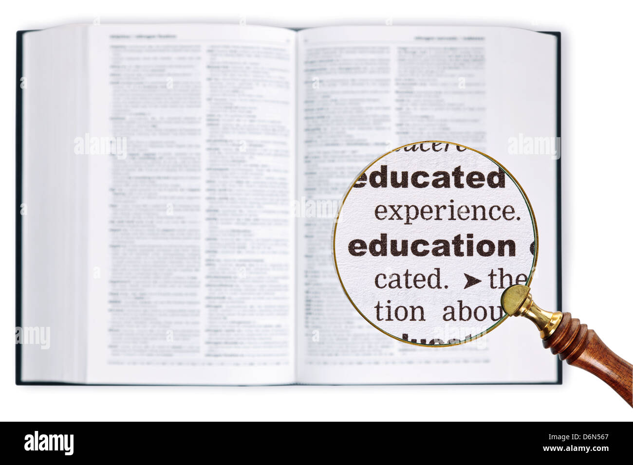 A magnifying glass held over a dictionary looking at the word Education enlarged Stock Photo