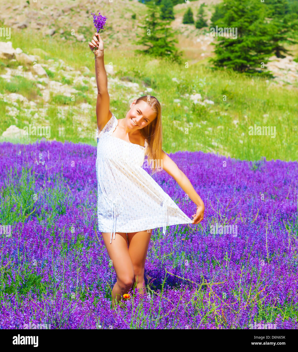 Pretty woman with lavender bouquet in hand dancing on purple flowers field, summer time holidays, leisure and freedom concept Stock Photo