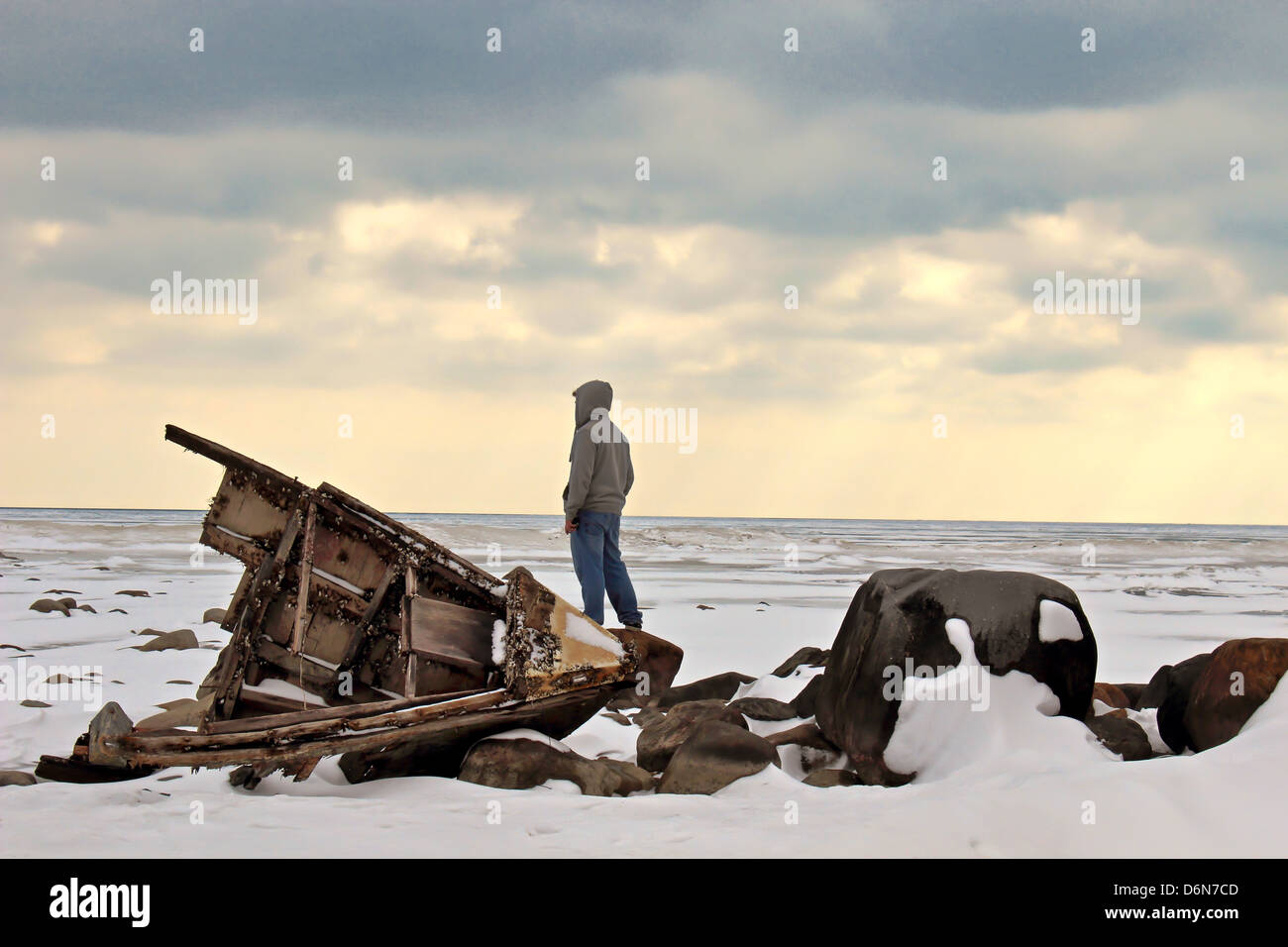 Adolescent male looking out over a frozen Lake Huron with a shipwreck in the foreground. Stock Photo