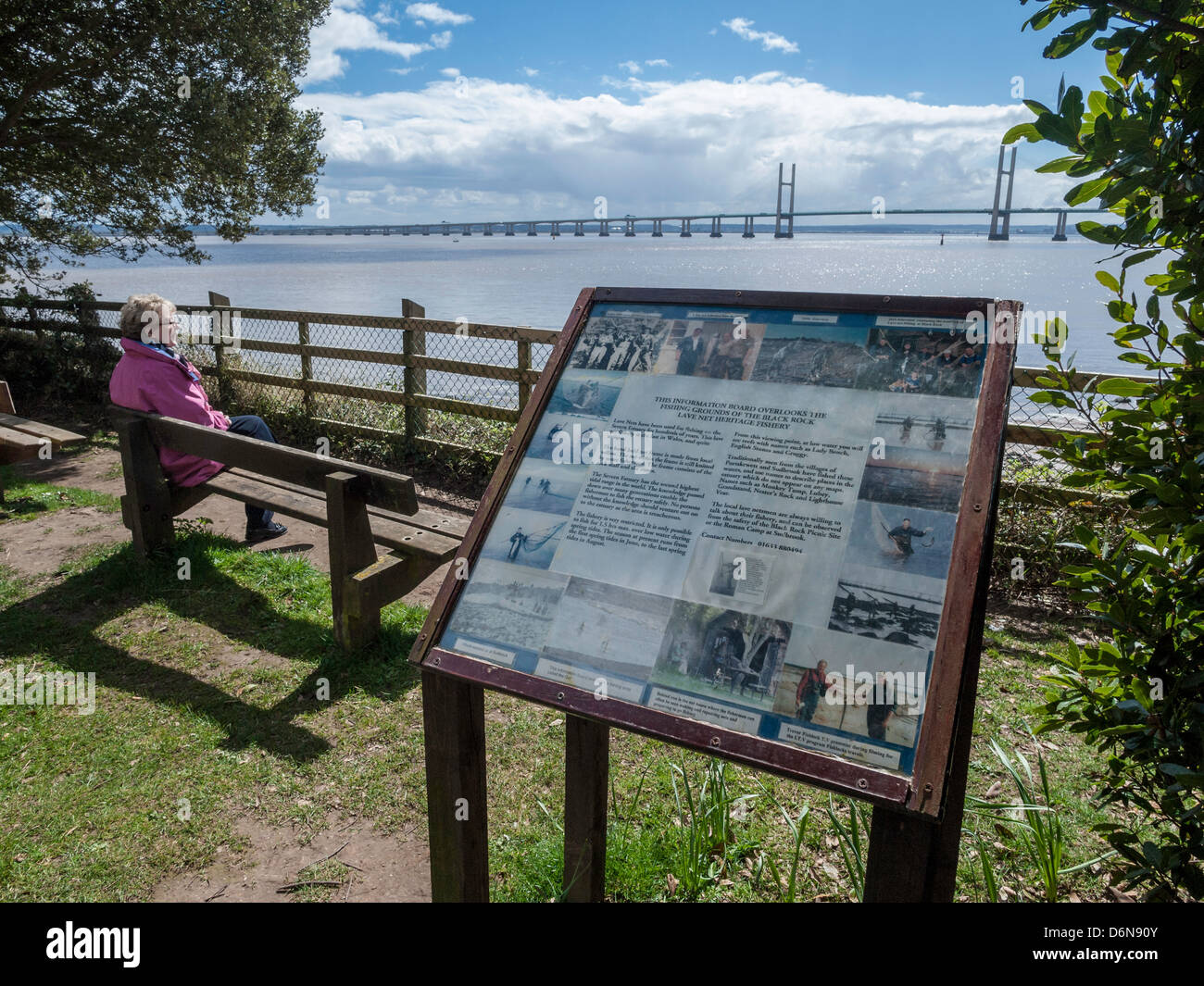 WALES COAST PATH AT BLACK ROCK WITH WALKER SITTING ON BENCH AND SECOND SEVERN CROSSING IN BACKGROUND. Stock Photo