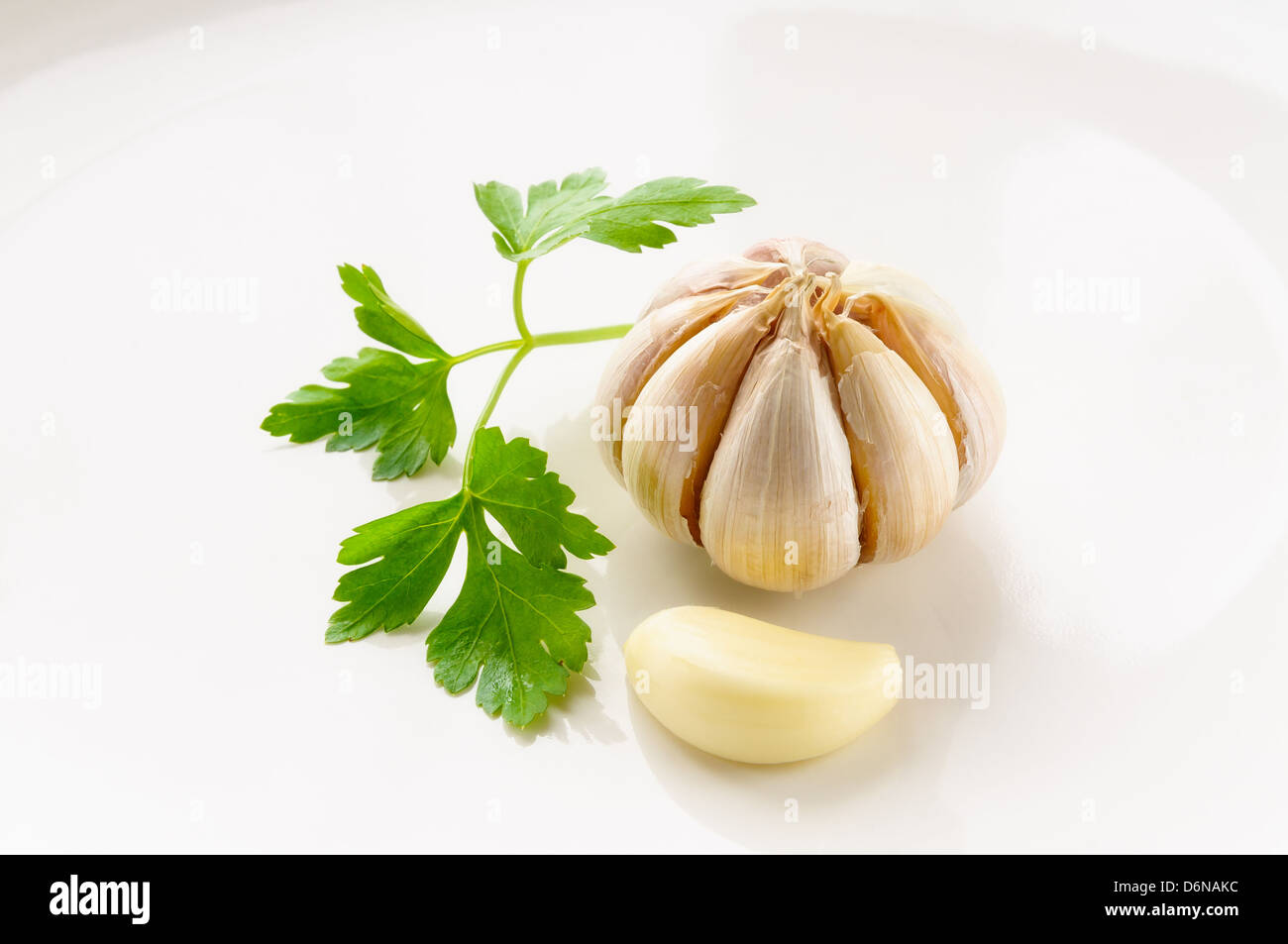 A clove of garlic and some leaves of parsley Stock Photo