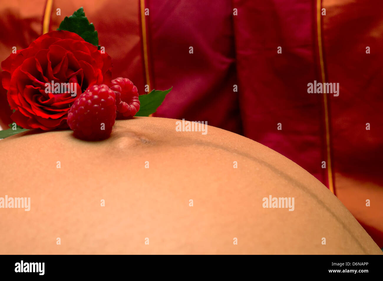 Rose and raspberries on the belly of a pregnant woman Stock Photo Alamy