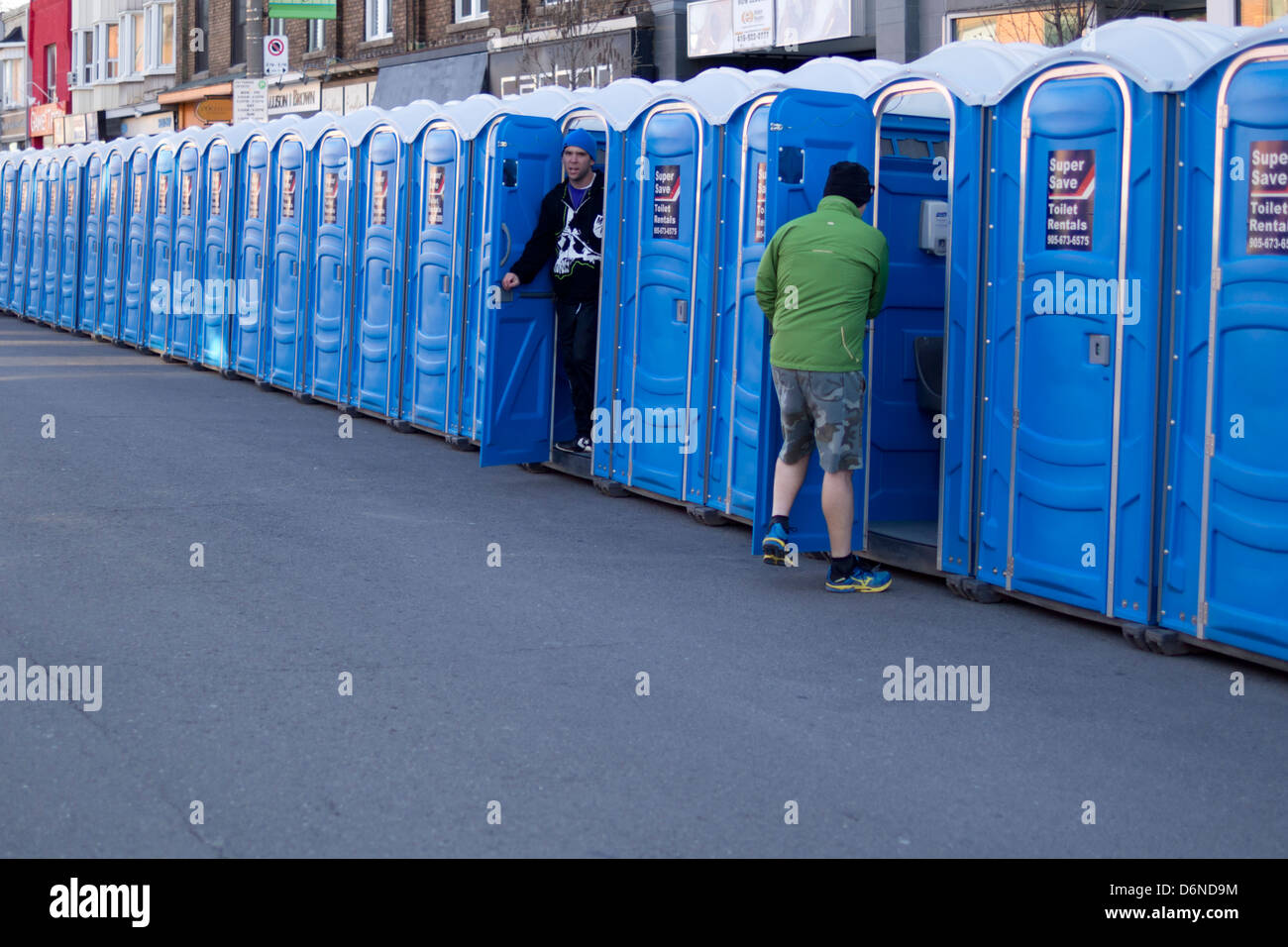 One person enters a portable toilet while another exits a portable