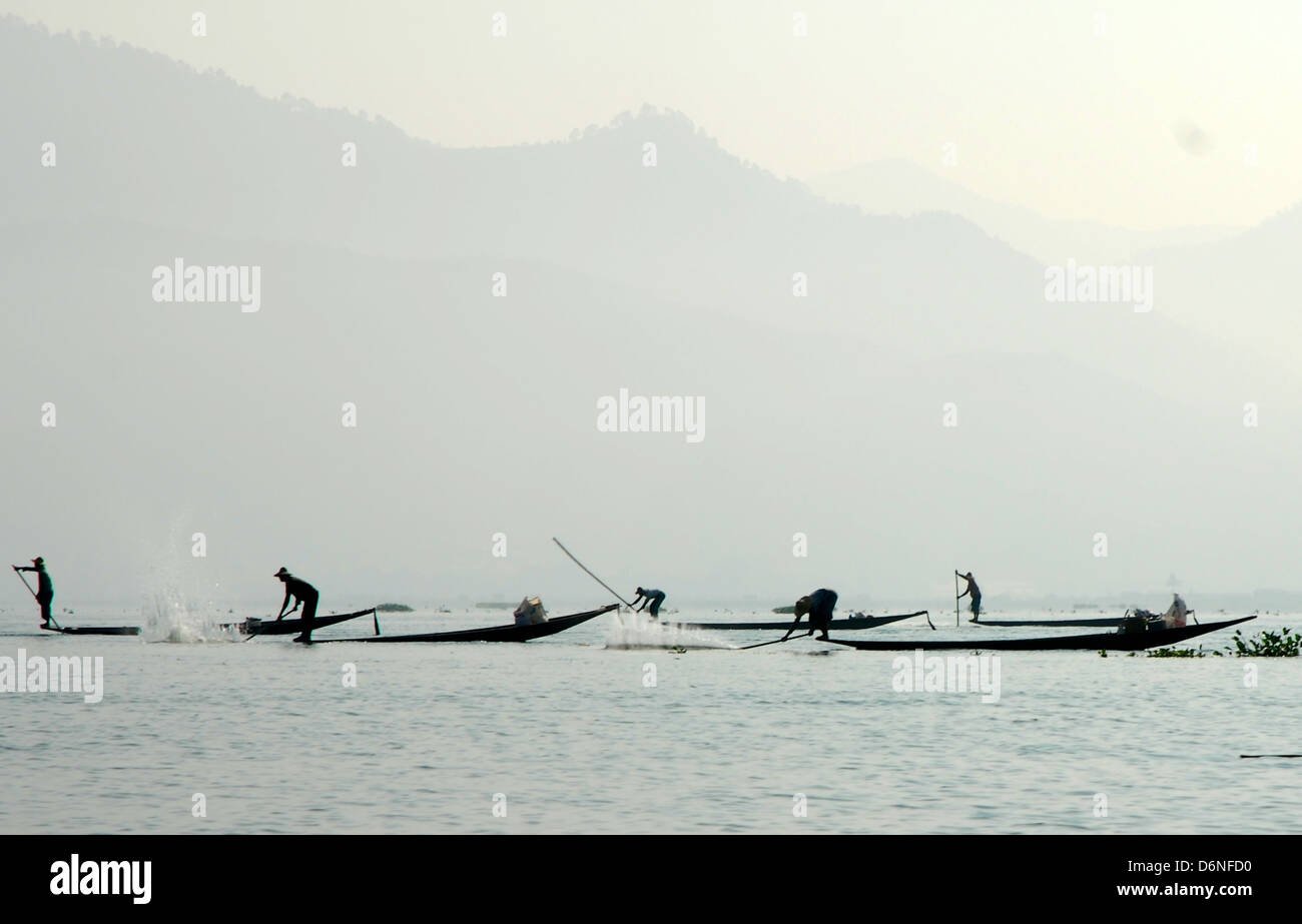 Fishermen on Inle lake beating water with bamboo poles to get the fish in their nets Stock Photo