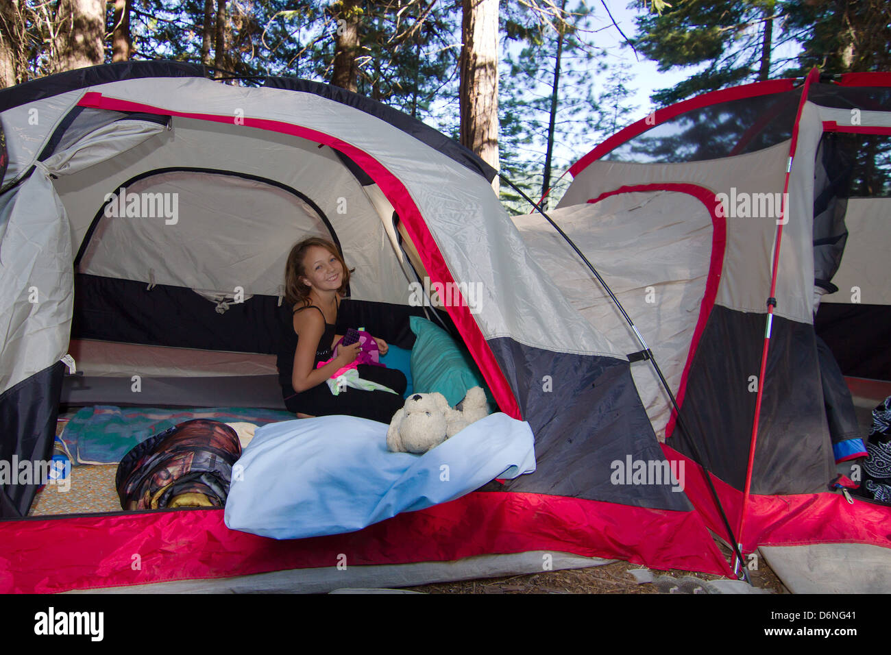 Campsite with tent and camping equipment. People relaxing around