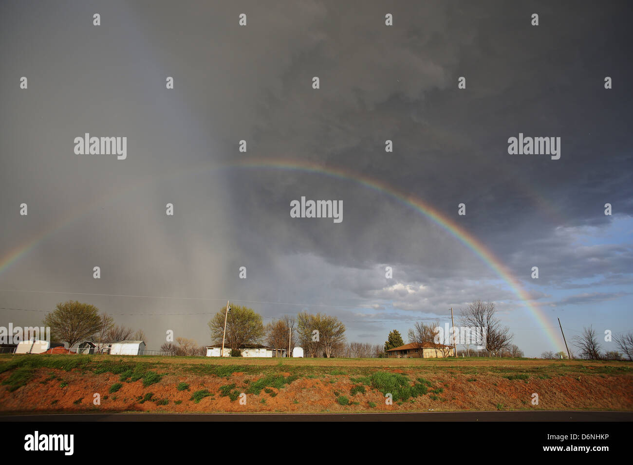 A double rainbow in a storm cloud over homes in rural Oklahoma. Stock Photo