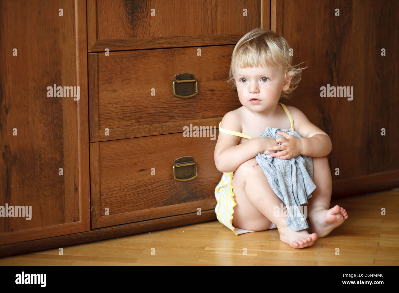 little girl sitting on floor looking sideways Stock Photo - Alamy