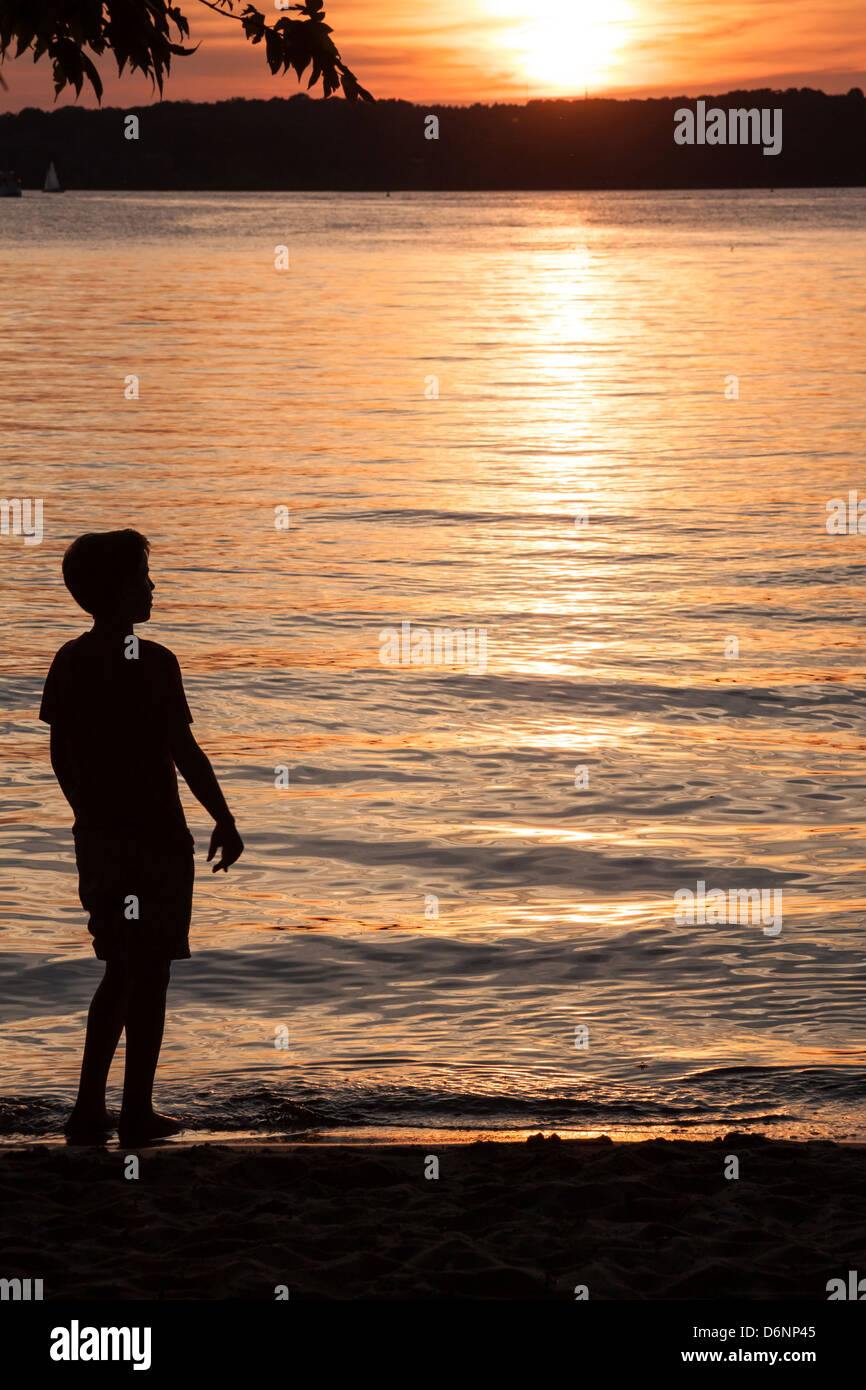 Berlin, Germany, a boy playing on the banks of the Havel river at sunset Stock Photo