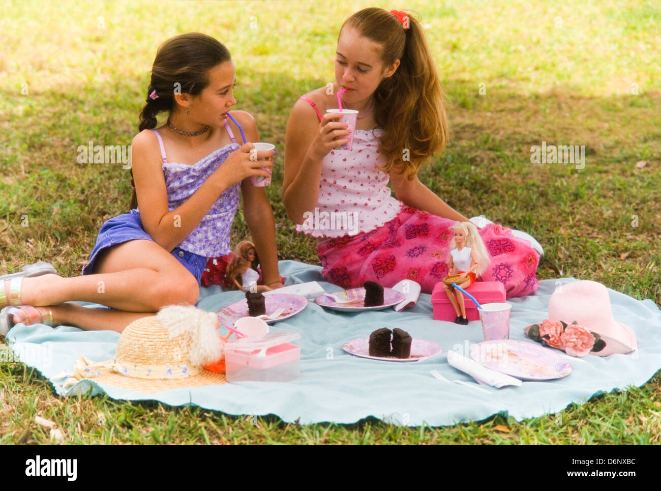 Teenage girls playing barbie dolls in park,having picnic, Miami Stock Photo