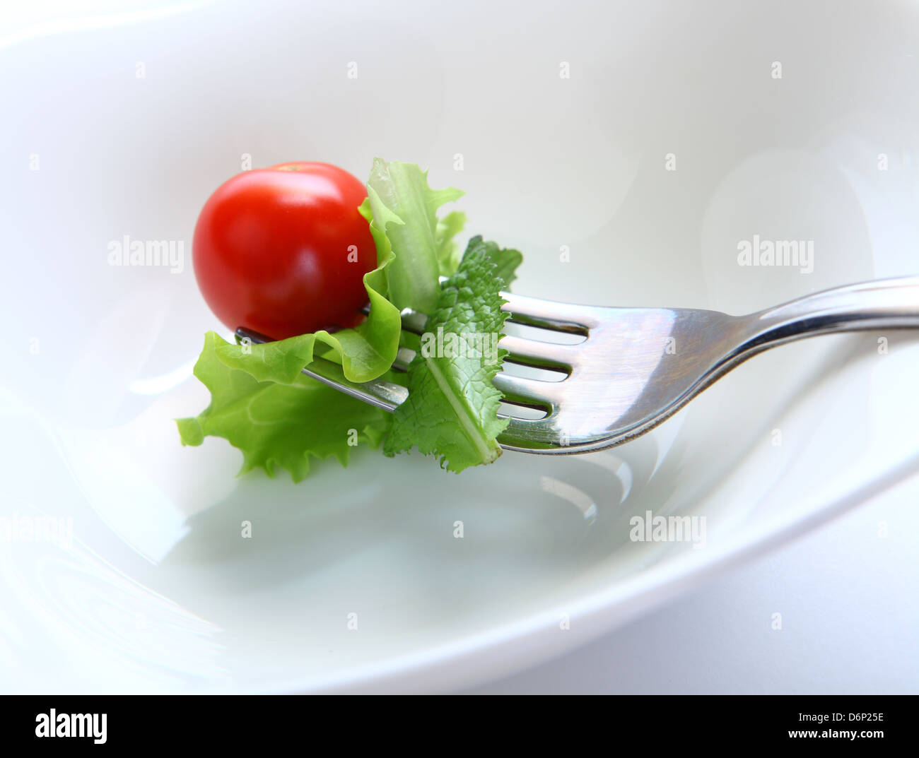 close-up of fork with cherry tomato and lettuce on the white background Stock Photo