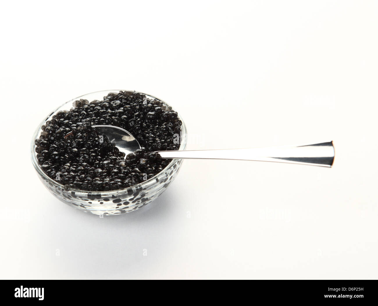 close-up of spoon and glass bowl with black caviar on the white background Stock Photo