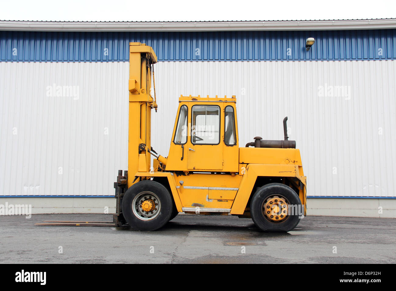 Yellow forklift truck by an industrial building. Stock Photo