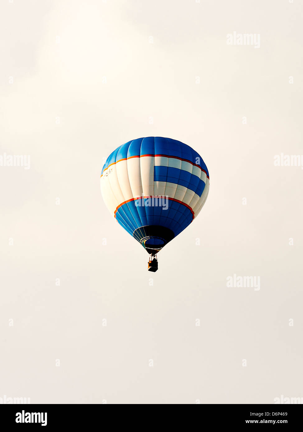 Blue and White Hot Air Balloon G-COSY Flying Over Alsager Cheshire With Grey Sky Behind England United Kingdom UK Stock Photo