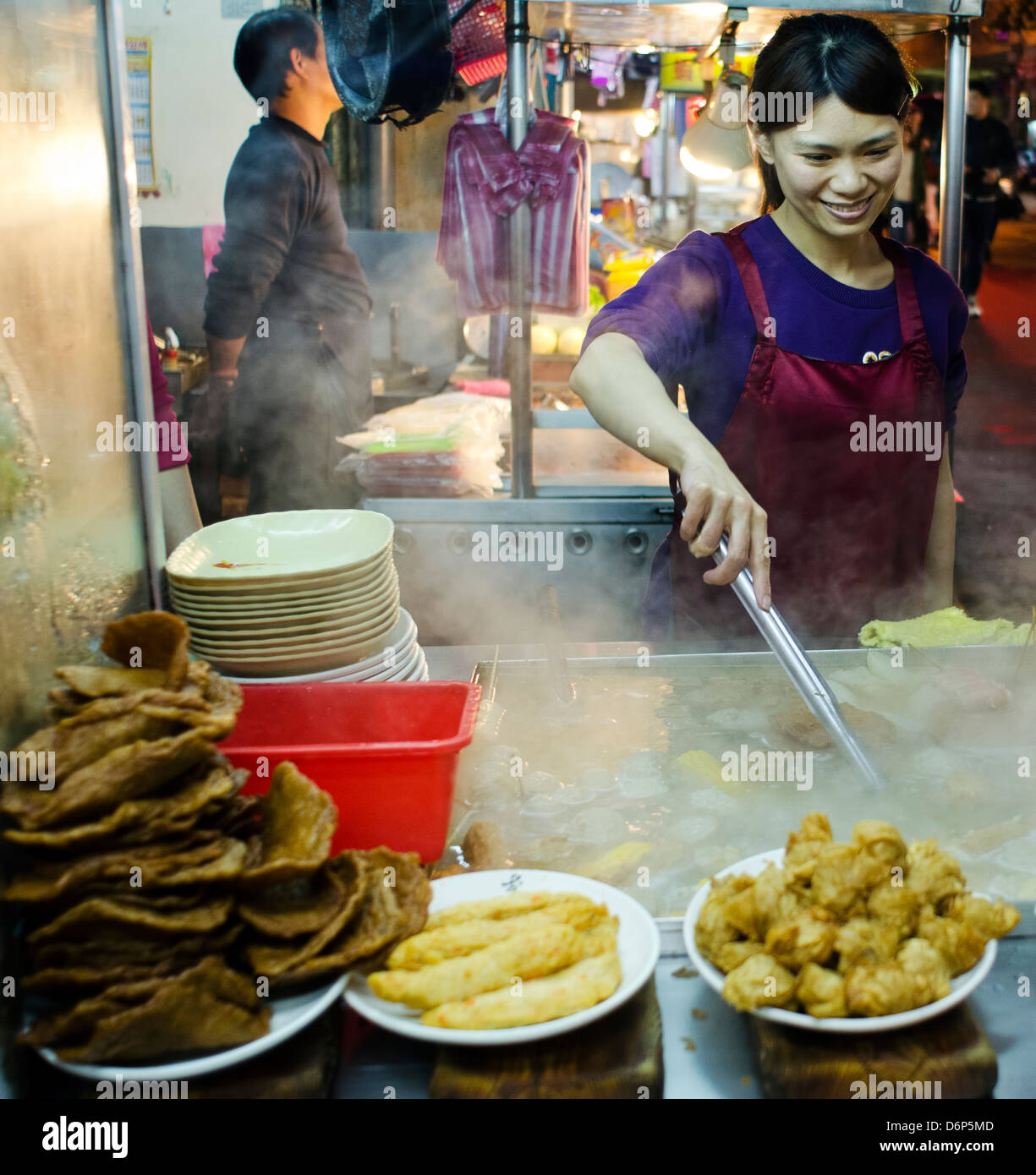 Beautiful girl preparing food at one of many stands on a food market, Taiwan. Stock Photo