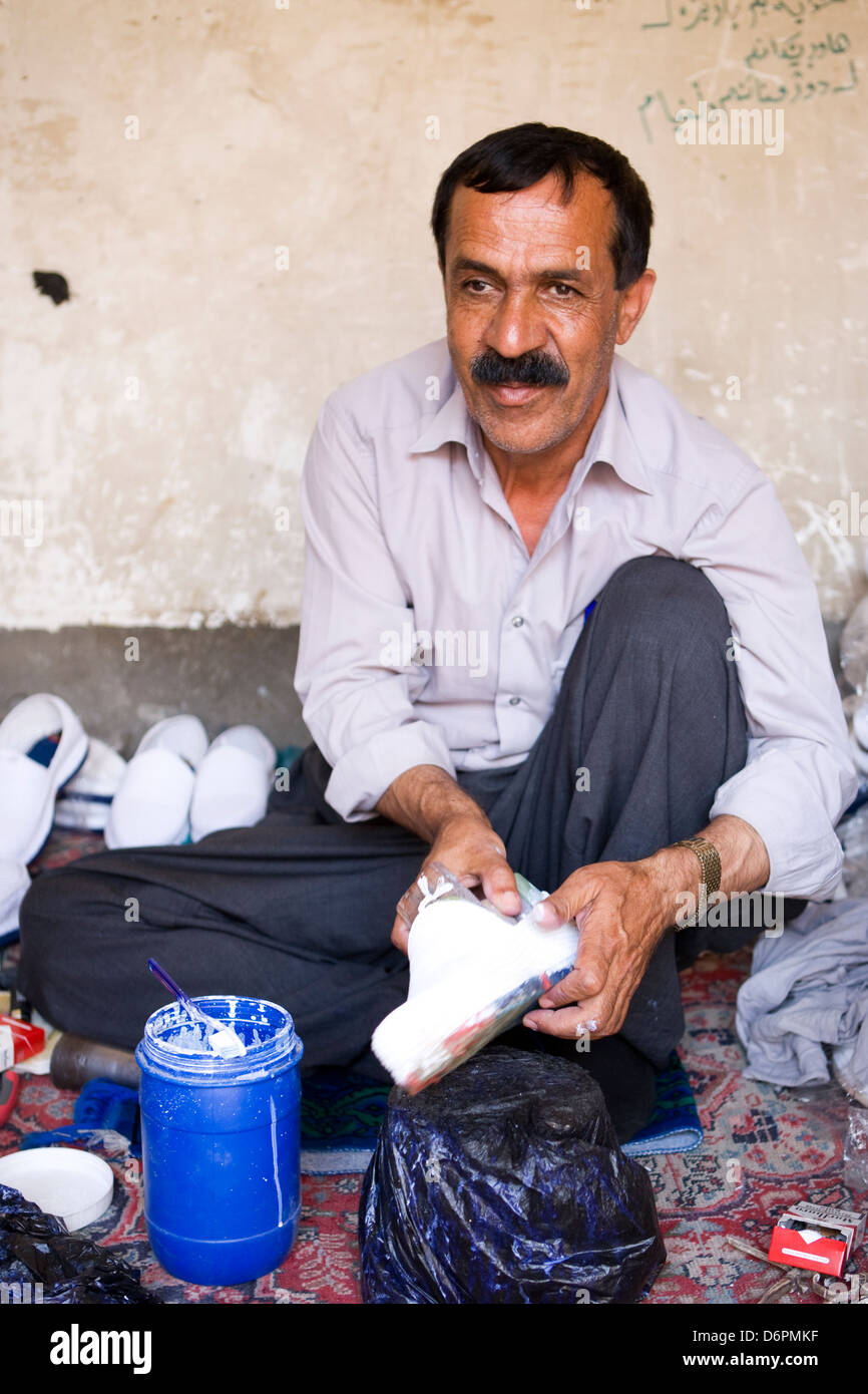 A blind Iraqi shoe maker in is shop by the ancient city of Citadel in Erbil, Iraq Stock Photo