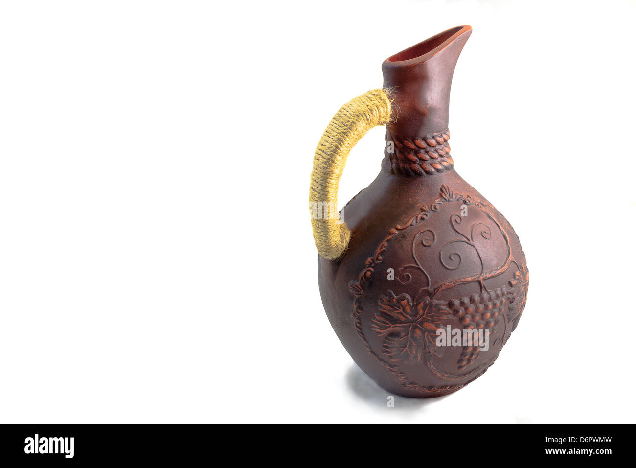 The jug for wine with the handle braided by a lace, is made of red clay, decorated with an ornament, presented on a white backg Stock Photo
