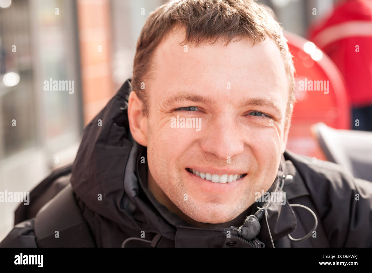 Close up city outdoor portrait of young smiling man in cold season Stock Photo