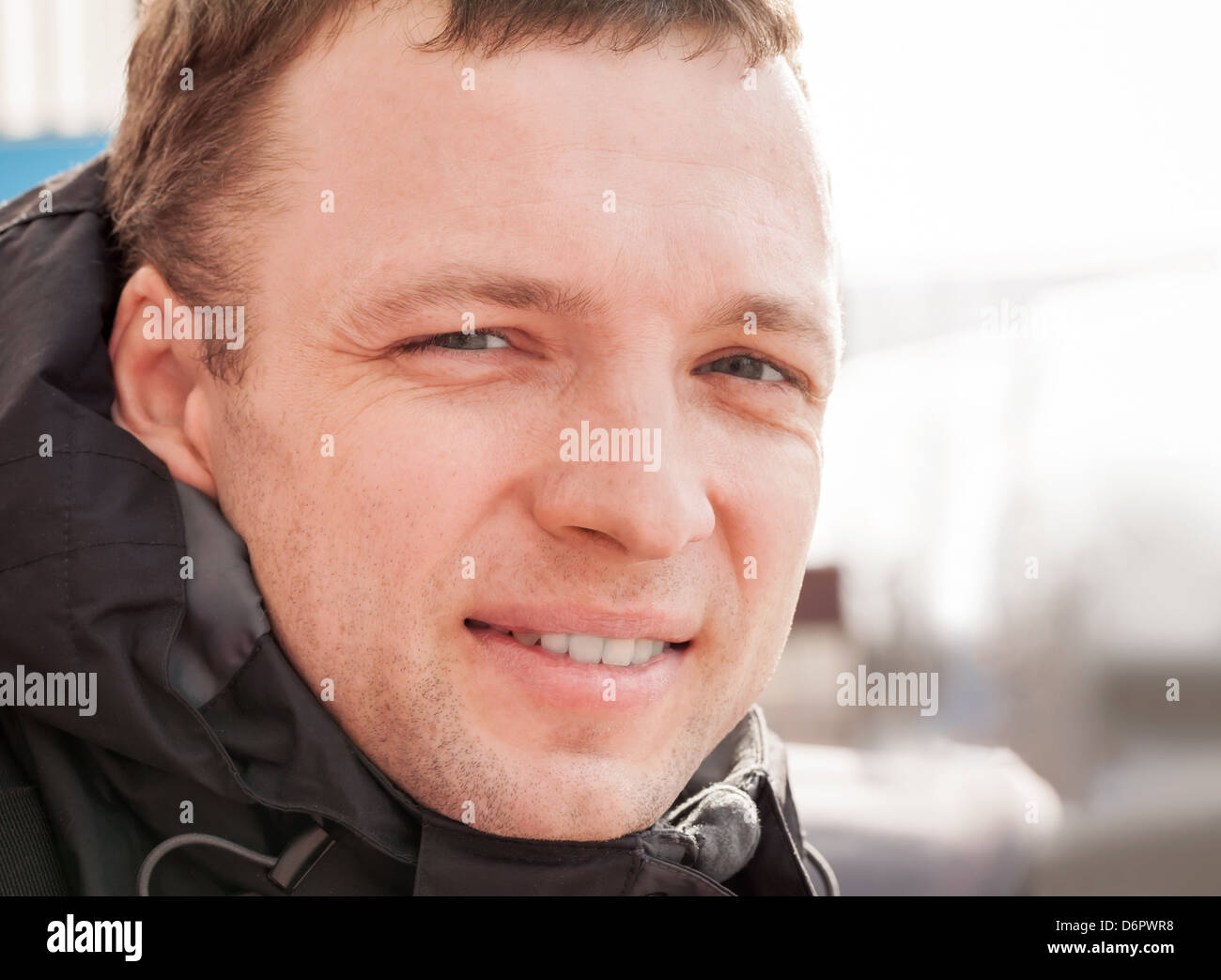 Close up outdoor portrait of young smiling man in cold season Stock Photo
