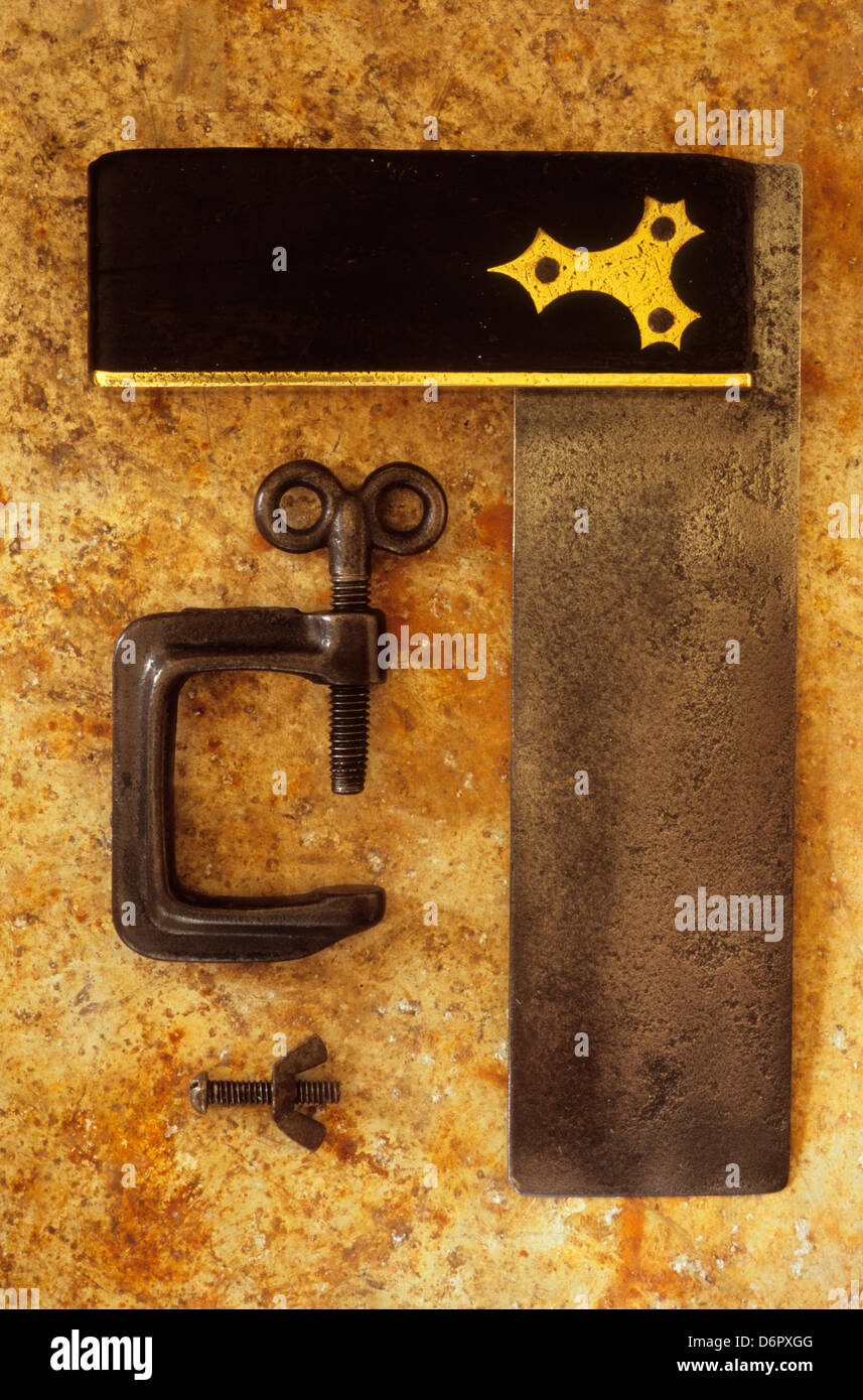 Close-up of G-clamp and small bolt with wingnut on a rusty stained metal sheet Stock Photo