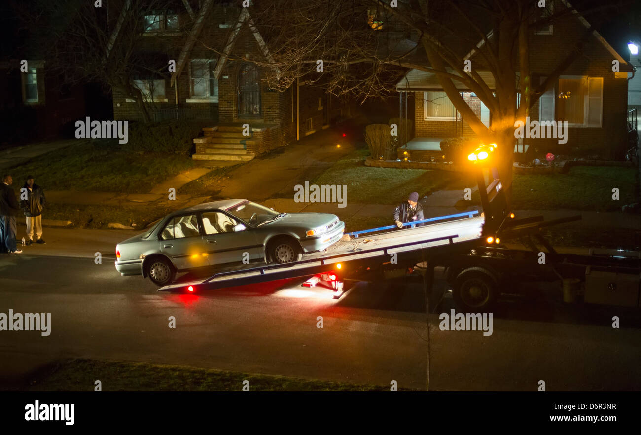 Detroit, Michigan - A worker loads a disabled car onto a truck at night in a residential neighborhood. Stock Photo