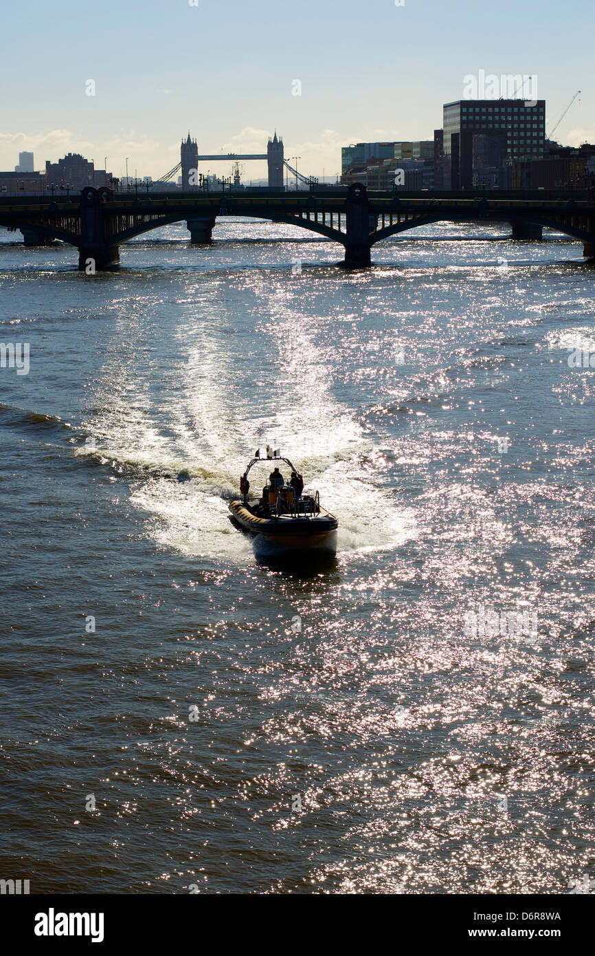 A speedboat on the River Thames set against the London skyline with Tower Bridge in the distance Stock Photo