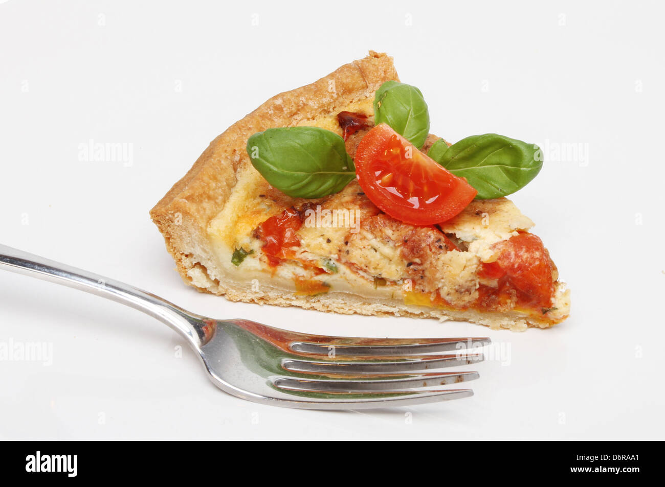 Slice of tomato, cheese and basil quiche on a plate with a fork Stock Photo