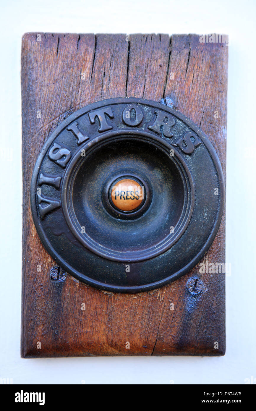 Door bell on wooden plinth with press written in the middle and visitors written around the outside Stock Photo