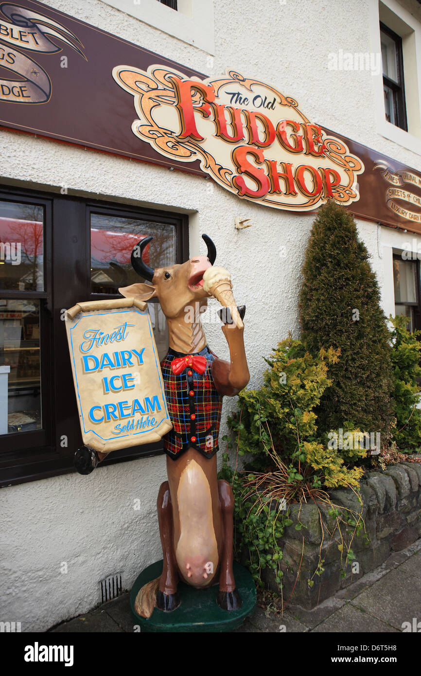 Model cow eating an ice cream cone outside a shop selling real dairy ice cream in the Scottish Trossachs town of Callander Stock Photo