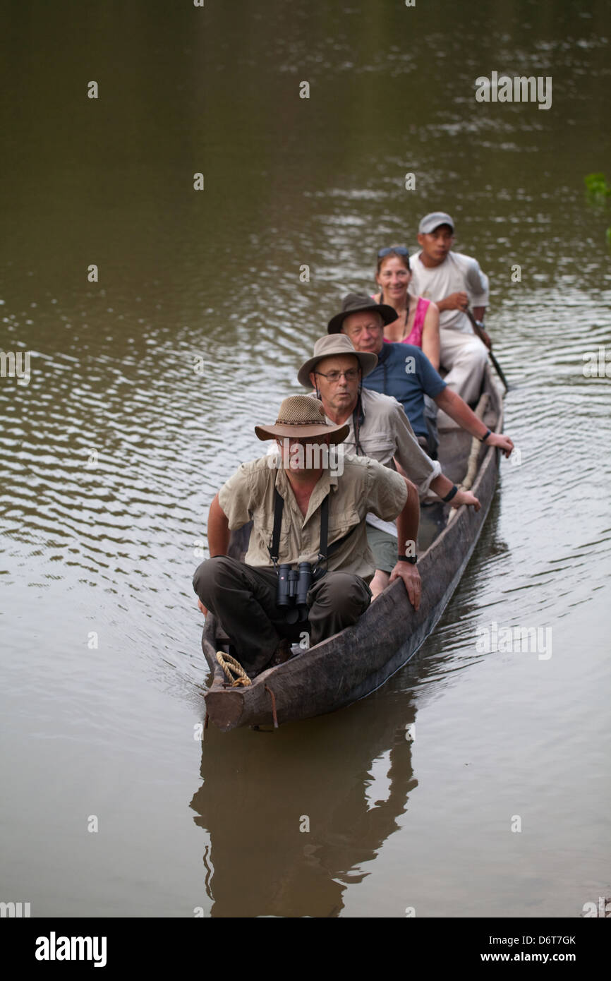 Eco-tourists with local Amerindian Guide paddling in a dugout canoe around an ox-bow lake deviating from the River Rewa. Guyana. Stock Photo