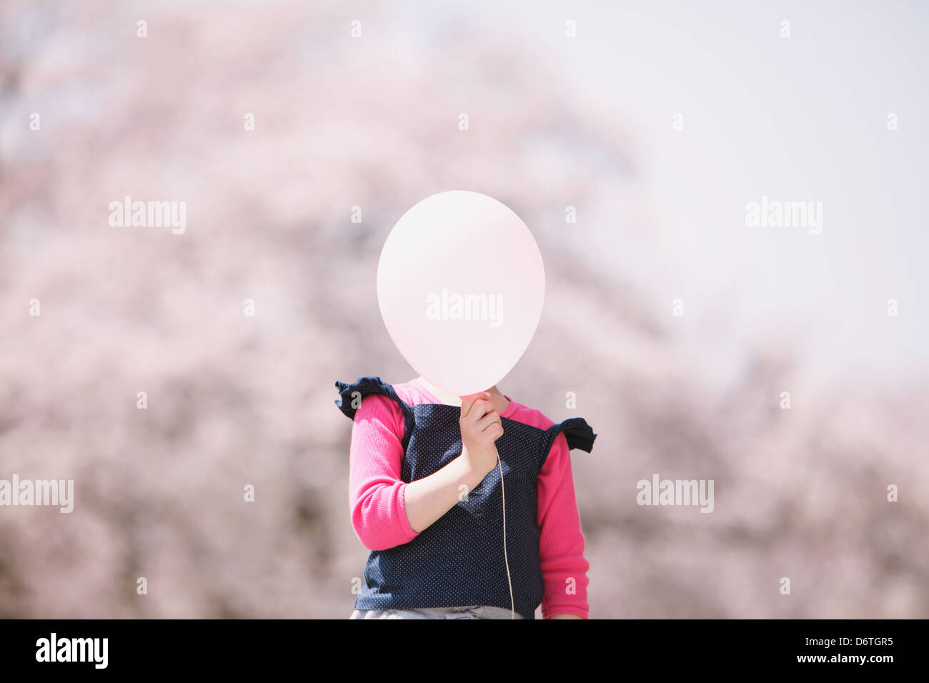 Young girl with balloon and cherry trees in the background Stock Photo