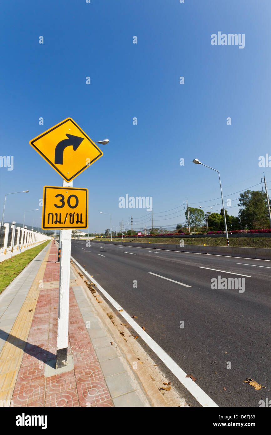 Road Sign warns Drivers to Limit Speed Ahead Dangerous Curve. Stock Photo