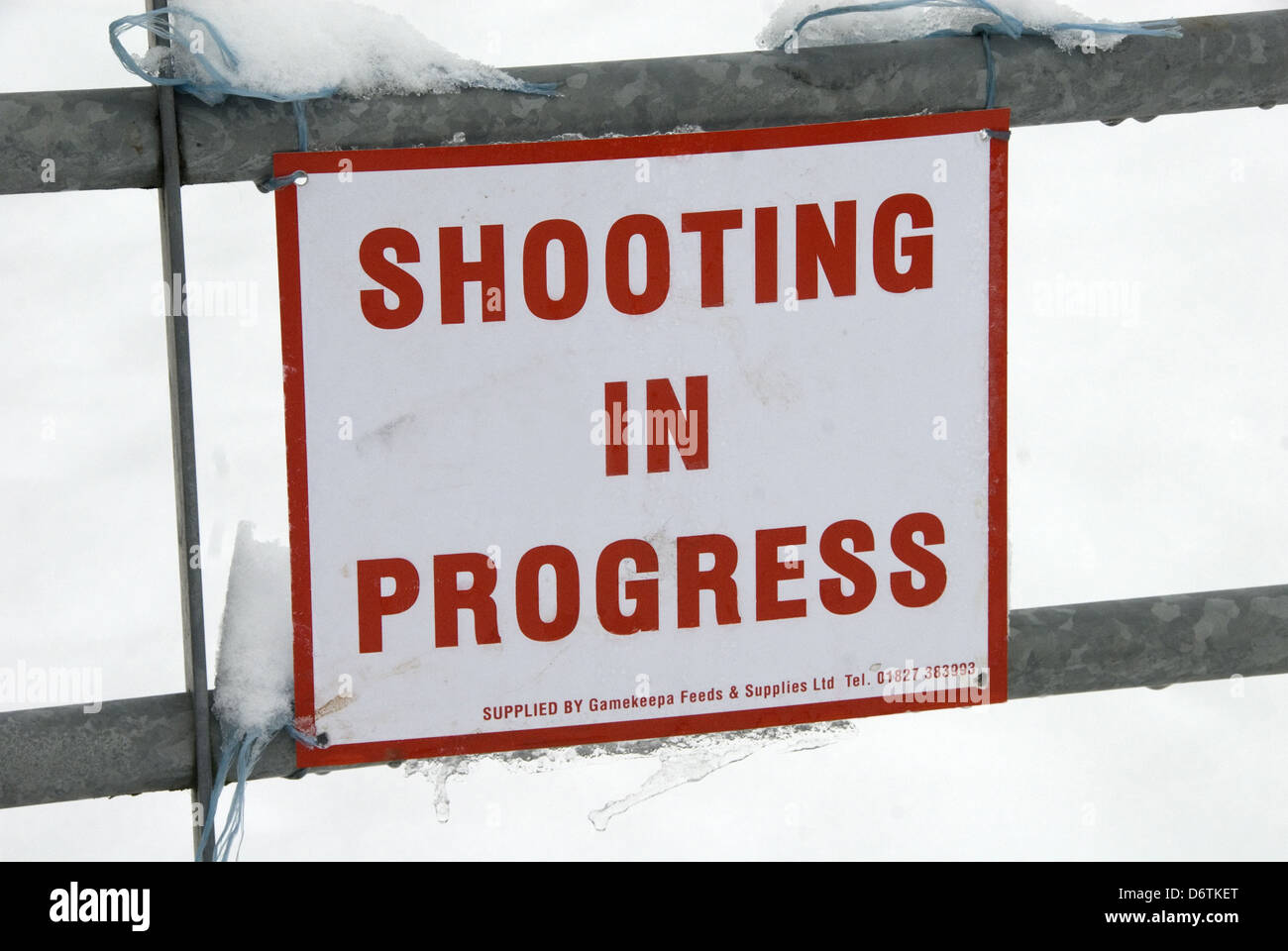 'Shooting In Progress' sign tied to gate in snow, warning of nearby shoot, near Mayfield, East Sussex, England, January Stock Photo