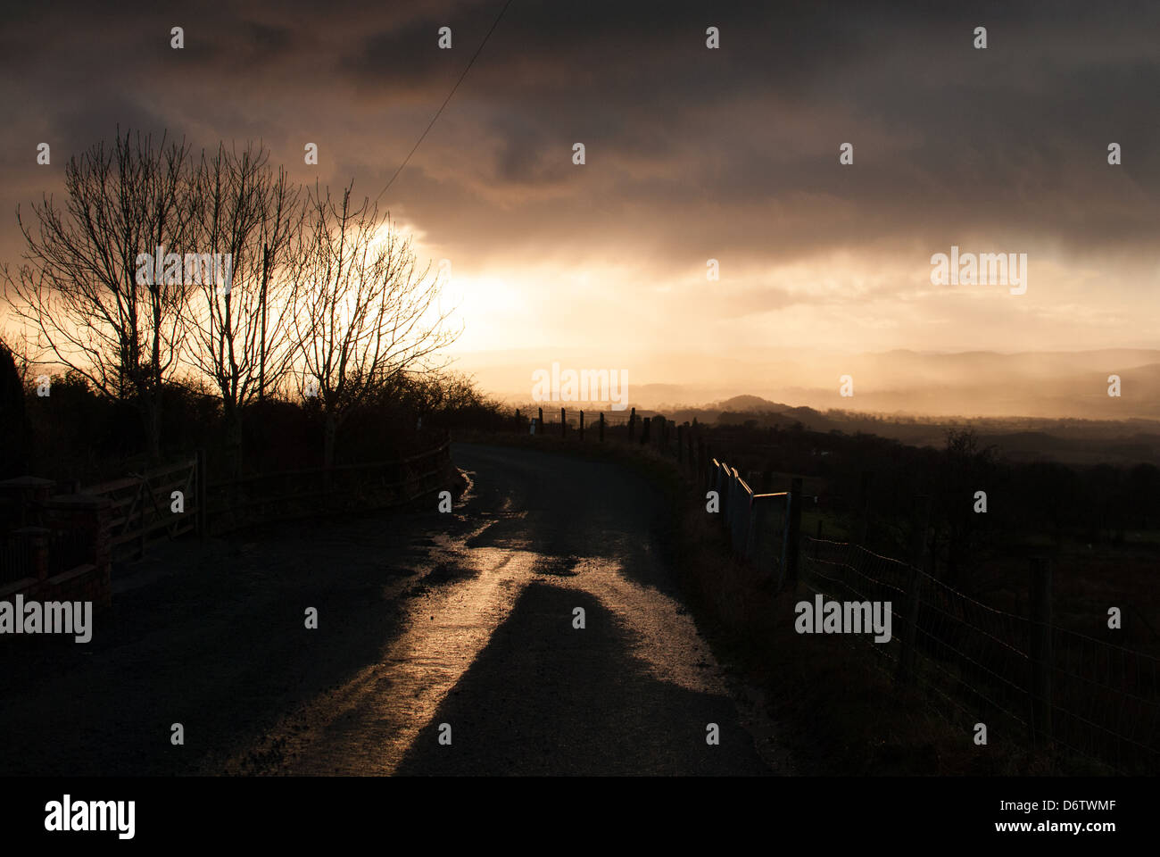 A misty golden sunset looking down the road from Clee Hill, Shropshire, England. Stock Photo