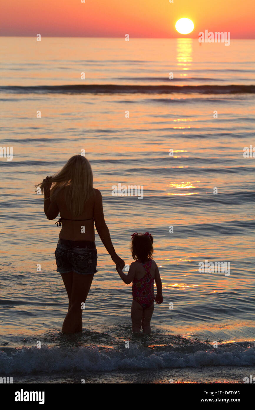 Mother And Daughter Holding Hands At Sunset At The Beach On The